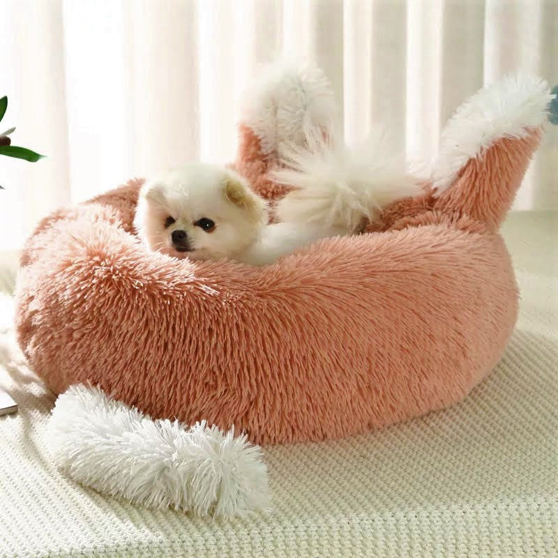 Small dog lying in a fluffy pink pet bed with white accents.